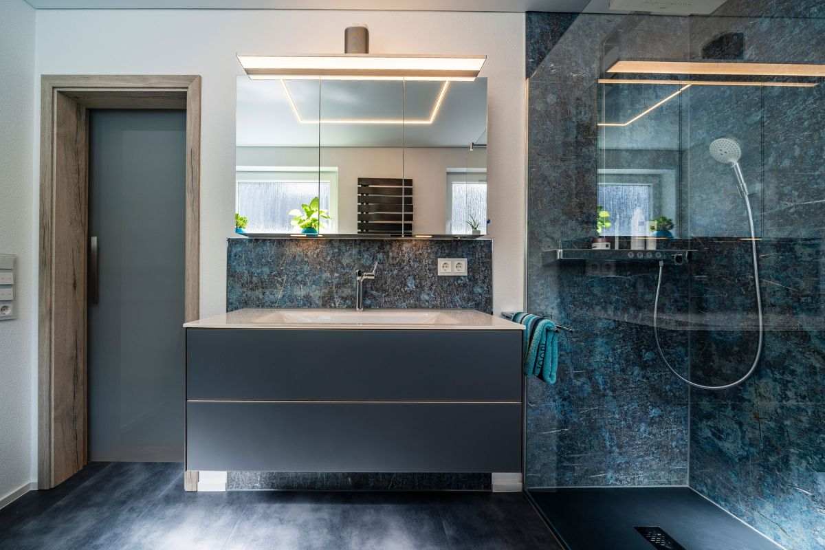 Bad mit dunkler Natursteinwand und bodengleicher Dusche
